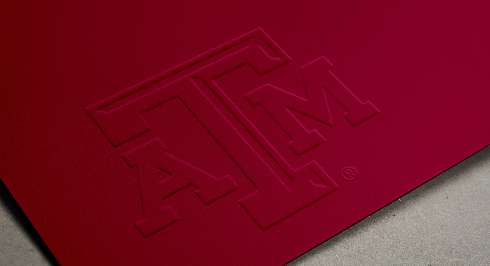 Maroon business card with embossed A&M logo