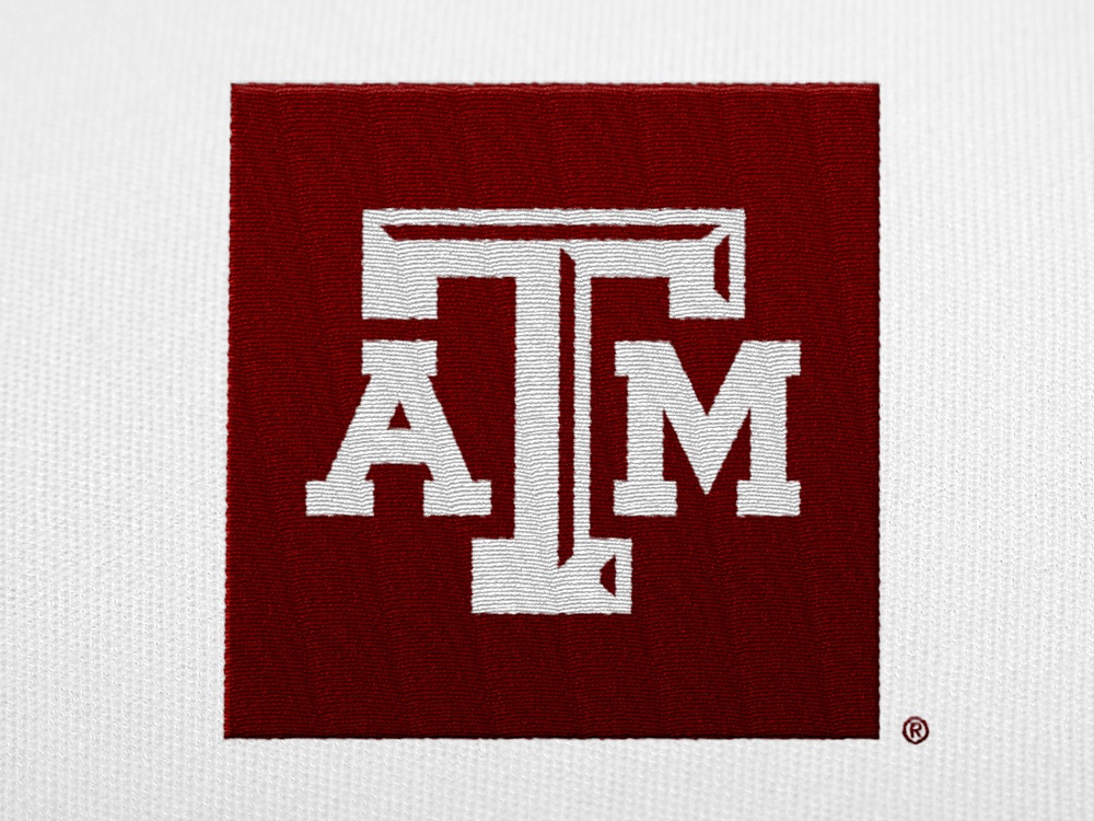 A white A&M logo with a maroon box embroidered on a white shirt
